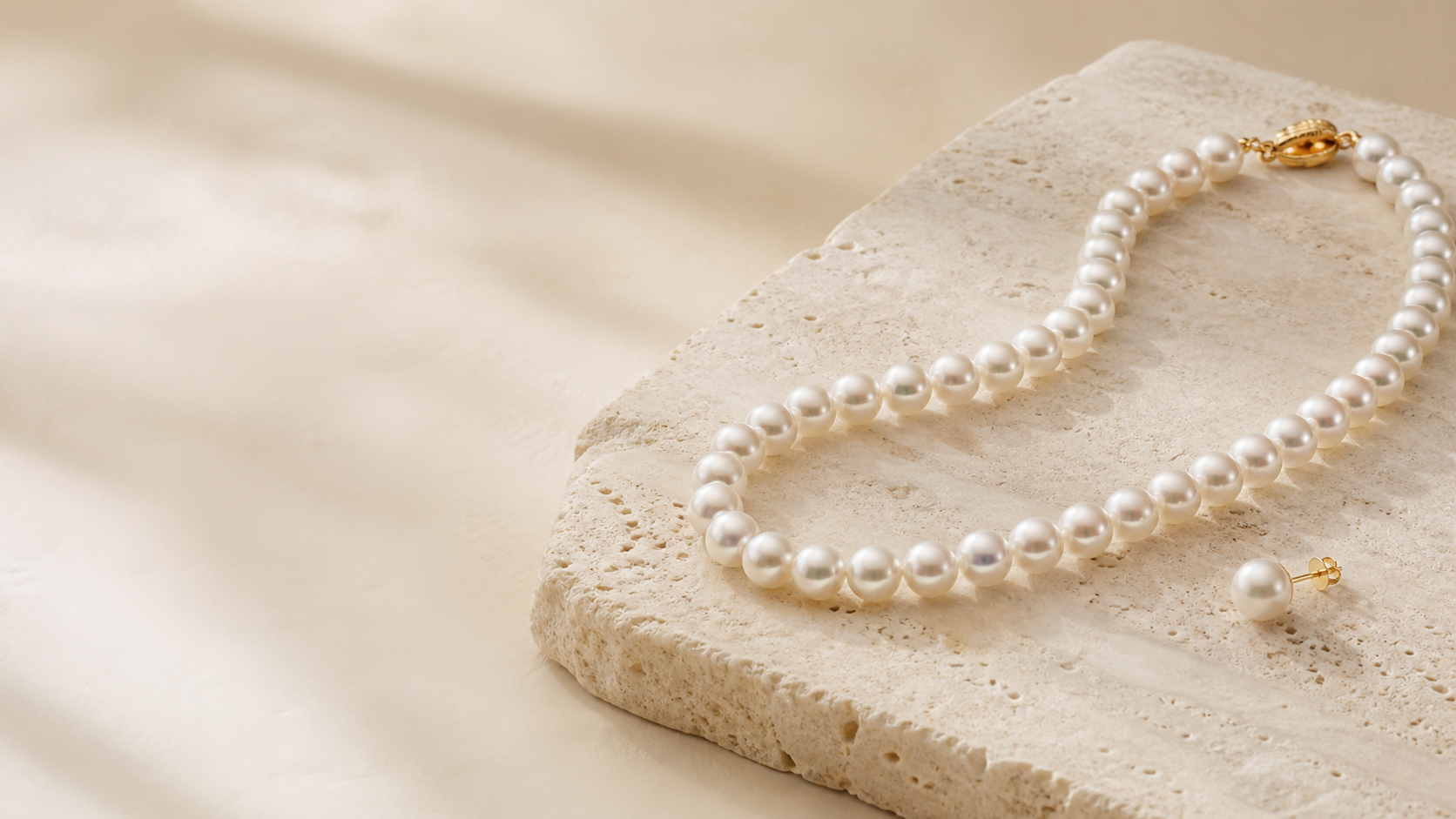 Cultured pearl strand and earring on warm stone